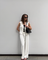 a lady wears a white suit vest with white loose fit trousers